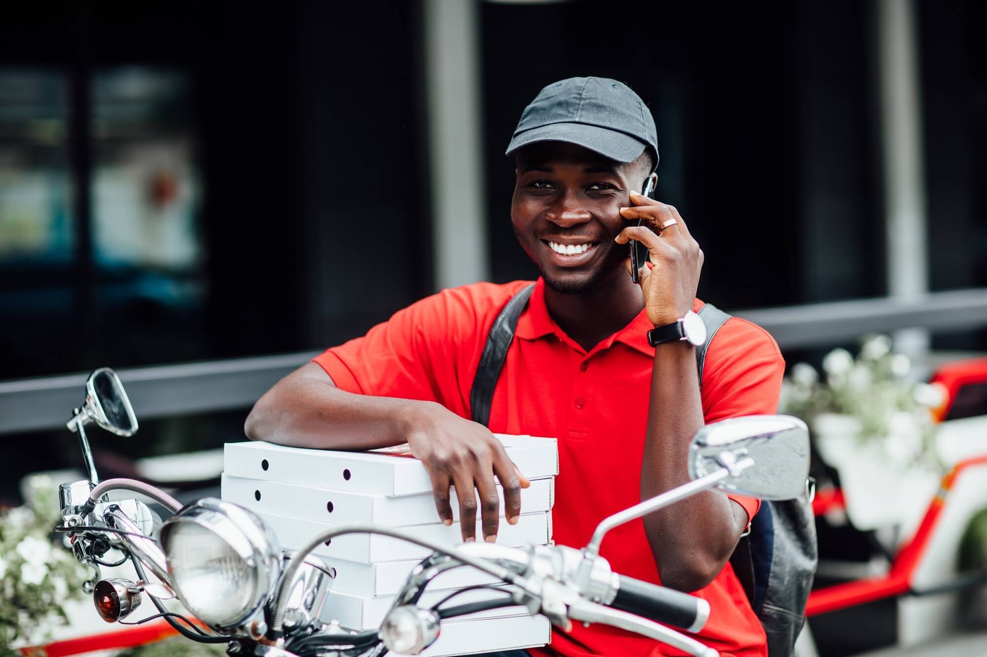 Livreur YoniFast au téléphone avec des colis sur une moto